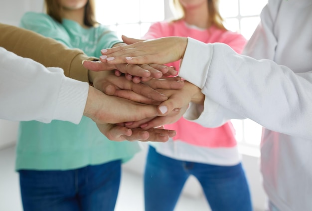 Foto gente uniéndose a las manos de mujeres jóvenes de pie juntas