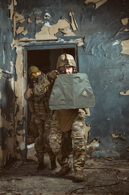 La gente de uniforme con armas en las ruinas.