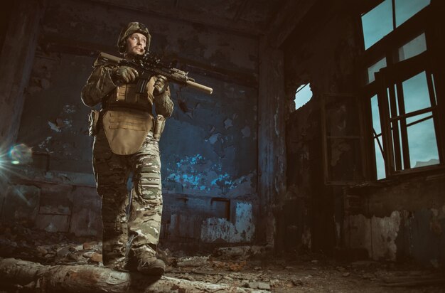 La gente de uniforme con armas en las ruinas.