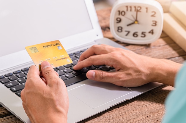 La gente usa tarjetas de crédito para comprar en línea a través de computadoras portátiles.