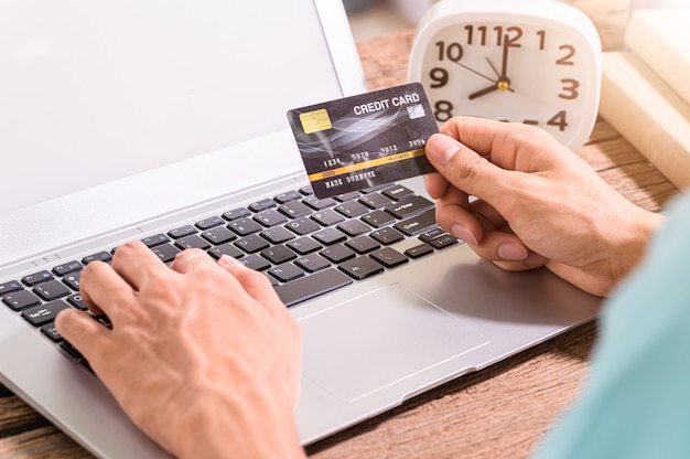 La gente usa tarjetas de crédito para comprar en línea a través de computadoras portátiles.