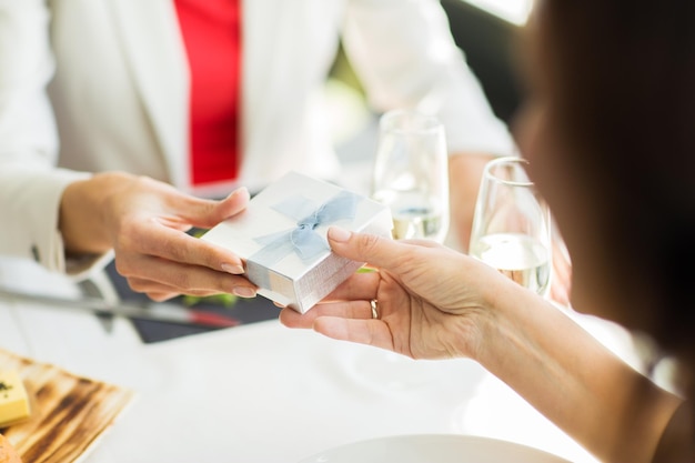 gente, vacaciones, celebración y concepto de estilo de vida - cerca de mujeres dando regalos de cumpleaños en el restaurante