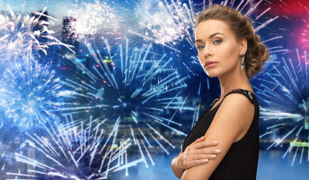 gente, vacaciones y concepto de glamour - hermosa mujer con aretes sobre fuegos artificiales en el fondo de la ciudad nocturna