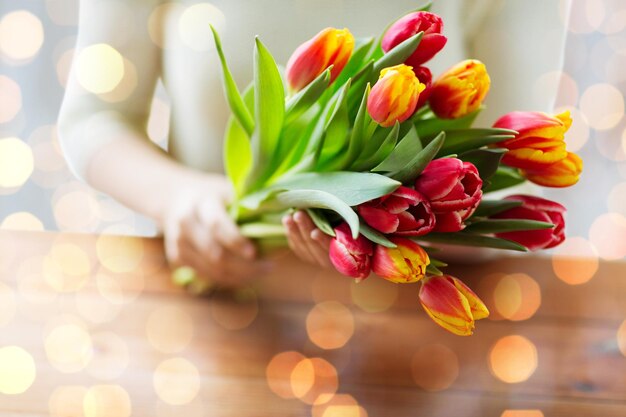 gente, vacaciones y concepto de jardinería - cerca de una mujer sosteniendo flores de tulipán