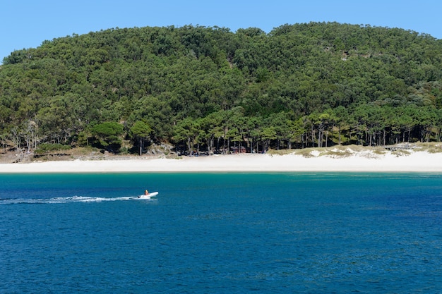 La gente viaja en un bote a motor inflable a lo largo de una orilla arenosa desierta hermoso paisaje natural