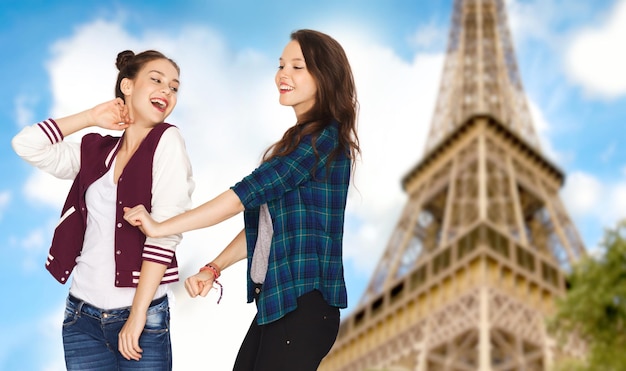 gente, viajes, turismo y concepto de amistad - felices y sonrientes adolescentes bailando sobre la torre eiffel en el fondo de parís