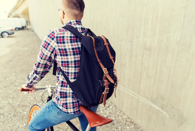 gente, viajes, turismo, ocio y estilo de vida - joven hipster con bicicleta fija y mochila en la calle de la ciudad