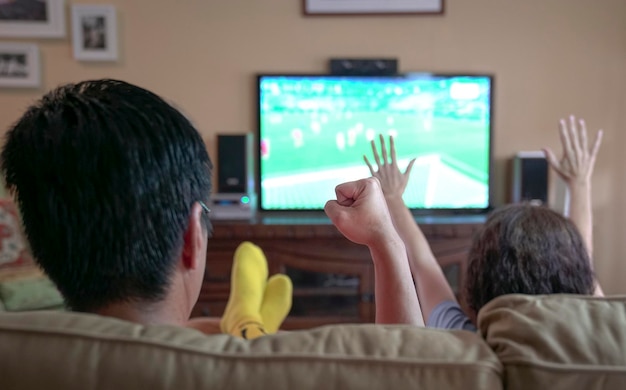 Gente viendo deportes en la televisión animando con el puño y las manos levantadas