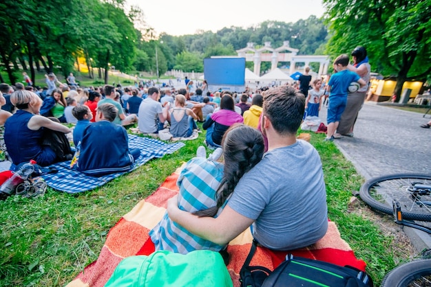 Gente viendo películas en cine al aire libre en el parque de la ciudad