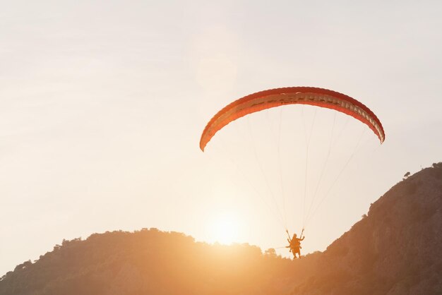 Gente volando un parapente en el cielo sobre las montañas