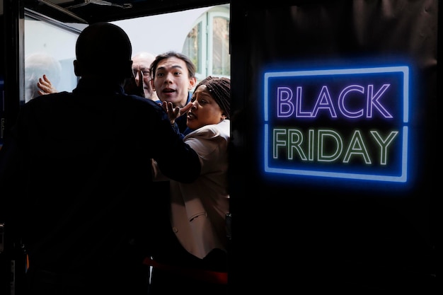 Foto la gente se vuelve loca por las ofertas del viernes negro, el oficial de seguridad del centro comercial maneja el control de multitudes, rechazando a los compradores ansiosos que intentan entrar en la tienda antes de que abra.