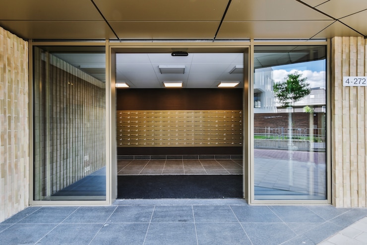Foto geöffnete glastür, die sich in die halle des modernen wohnhauses auf der stadtstraße lehnt