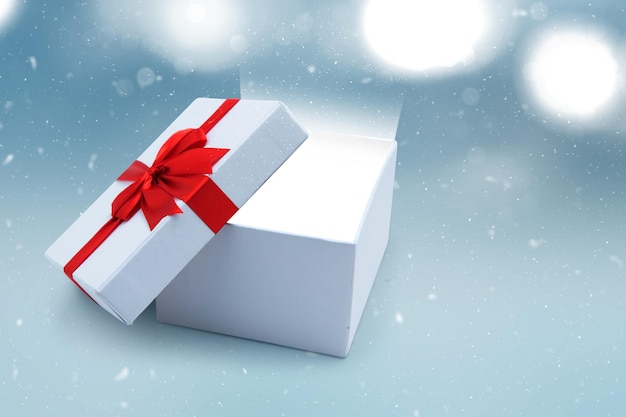 Geöffnete weiße Geschenkbox mit rotem Band mit unscharfem hellem Hintergrund