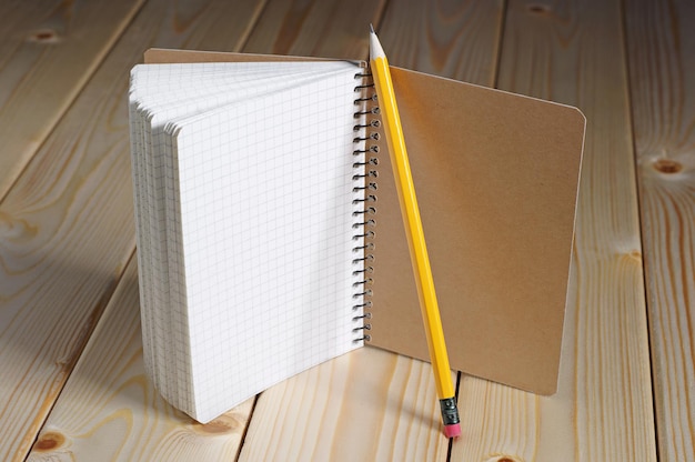 Geöffneter Notizblock und Bleistift auf einem Holztisch. Es gibt Platz für Ihren Text