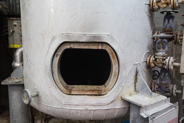 Geöffneter rostiger Mannloch auf dem engen Raum des weißen Kraftstofftanks