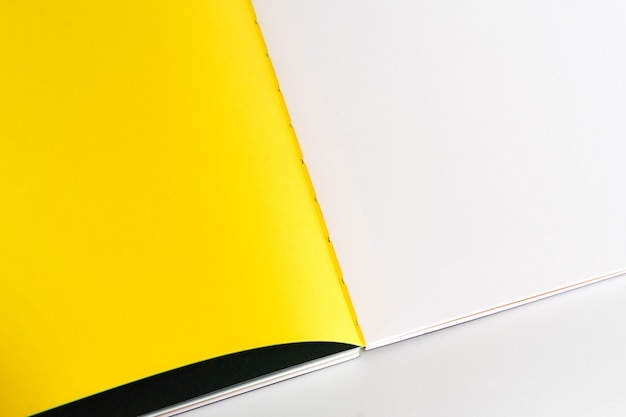 Geöffnetes leeres Buch am weißen gelben Designpapierhintergrund.