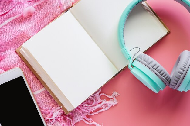 Foto geöffnetes notizbuch mit kopfhörern und smartphone auf kleinem schal und rosa hintergrund
