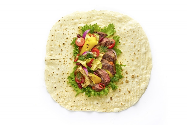 Geöffnetes Tortilla-Wrap-Sandwich mit saftigem Steak, gegrilltem Gemüse, Kirschtomaten, Salatsalat und Kräutern, Draufsicht