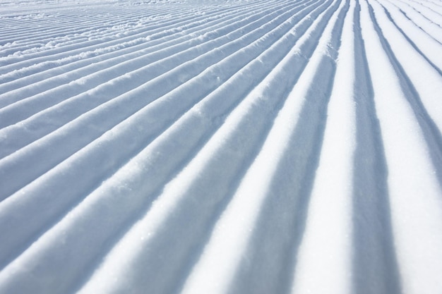 Geometriespurlinien auf einer Skipiste, die von einer Pistenraupe als Texturhintergrund hinterlassen wurde