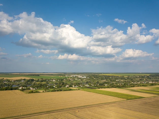 Geometrische abstrakte Formen von landwirtschaftlichen Feldern in grüngelben Farben, Landschaftslandschaft gegen blauen bewölkten Himmel. Eine Vogelperspektive von der Drohne.