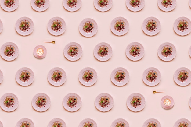 Geometrisches Muster mit Pfannkuchen auf rosa Platte und Tasse Kaffee auf rosa Hintergrund.