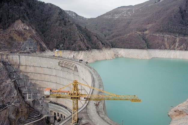 GEORGIA, SVANETI, MESTIA. Vista de cima da Represa Enguri sobre as montanhas no primeiro plano do guindaste amarelo