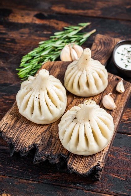 Georgische Khinkali-Knödel mit Rind- und Lammfleisch auf Holzbrett mit Kräutern