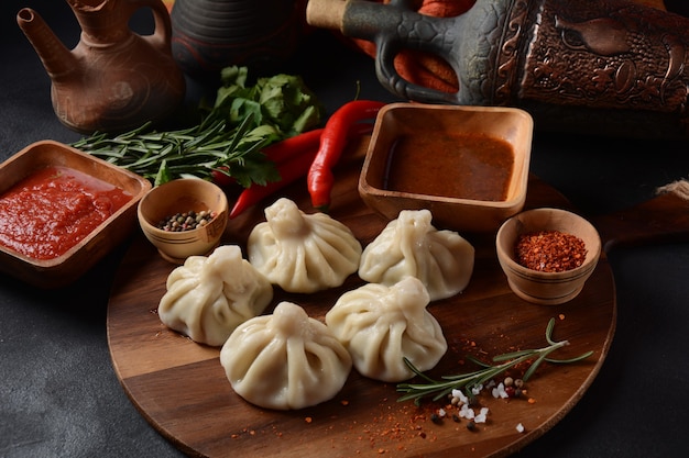 Georgische Teigtaschen Khinkali mit Fleisch und rotem Pfeffer, traditionelle georgische Küche. Khinkali mit lokalen Saucen - Tkemali, Satsebeli, Adzhika.