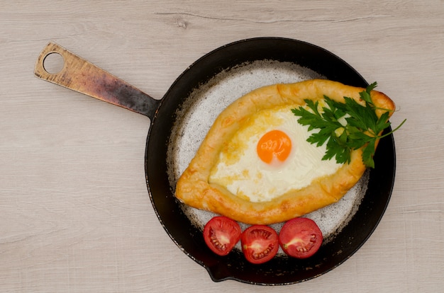 Georgisches Khachapuri mit Käse und Tomaten in einer Pfanne