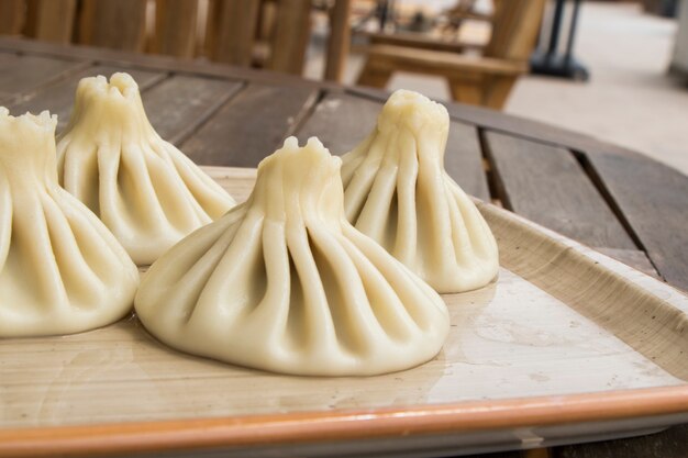 Georgisches traditionelles Essen Khinkali auf dem Teller im Restaurant, essfertig, warmes Gericht auf dem Holztisch.