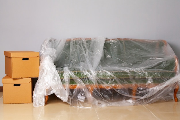 Gepackte Haushaltsgegenstände in Kisten und gepacktes Sofa zum Umziehen