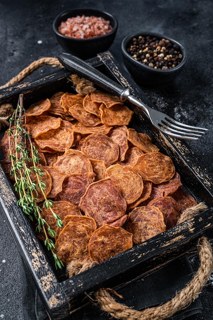 Foto gepökeltes rindfleisch und schweinefleisch jerky in einem holztablett. schwarzer hintergrund. ansicht von oben.