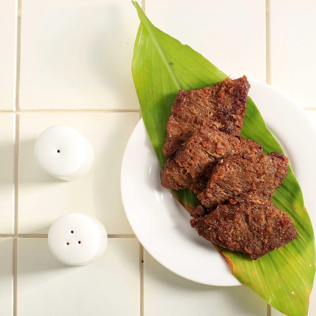 Gepuk é um alimento tradicional indonésio feito de carne com um sabor doce e salgado, normalmente também chamado de Empal. Gepuk significa esmagar a carne até ficar macia. Servido em Prato Branco, Foto Isolada