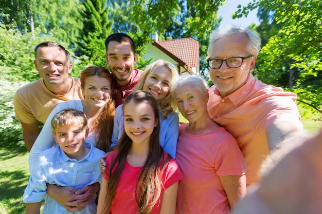 Foto geração e conceito de pessoas - família feliz tirando selfie no jardim de verão