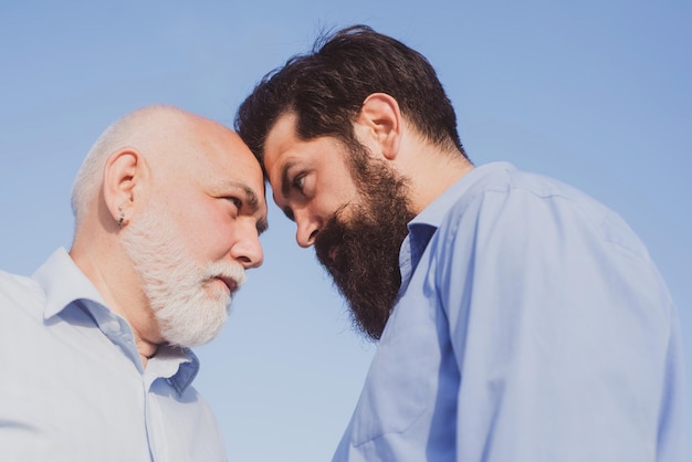 Gerações de homens envelhecem avô e pai juntos Avô e pai felizes sobre o fundo do céu azul e nuvens