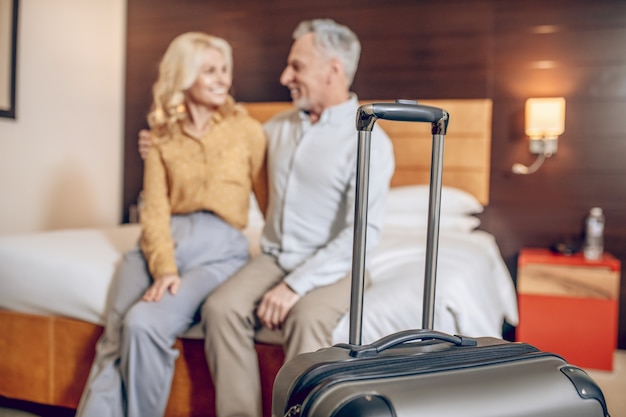 Gerade angekommen. Ein gutaussehendes Paar sitzt auf einem Bett in einem Hotelzimmer