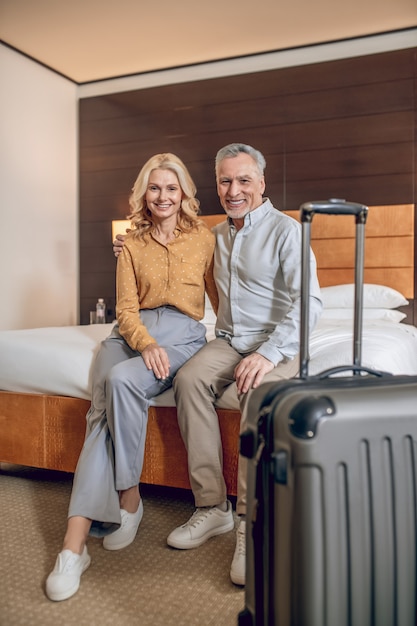Gerade angekommen. Ein gutaussehendes Paar sitzt auf einem Bett in einem Hotelzimmer