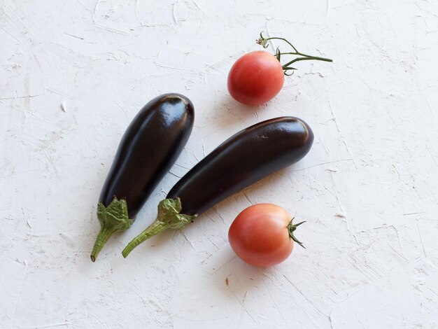 Gerade gepflückte Tomaten und Auberginen auf dem weißen strukturierten Hintergrund Gerade geerntetes Gemüse