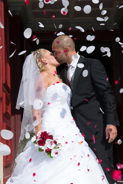 Gerade verheiratetes Paar unter einem Regen von Rosenblättern