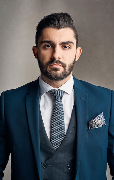 Geradliniger Stil und Erfolg Studioporträt eines stilvoll gekleideten und selbstbewussten jungen Geschäftsmannes, der vor einem grauen Hintergrund posiert