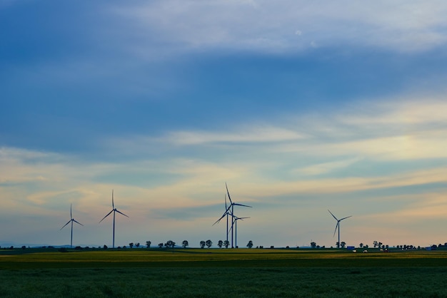 Gerador de turbina de moinho de vento contra belo céu pôr do sol no conceito de área rural de renovação limpa