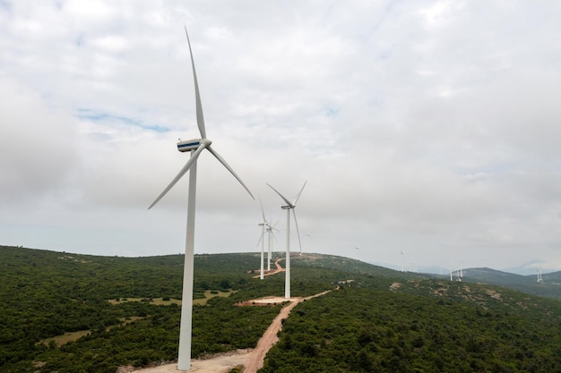 Gerador eólico Turbina eólica na estrada curva na colina Planta de energia alternativa grega Fazenda eólica