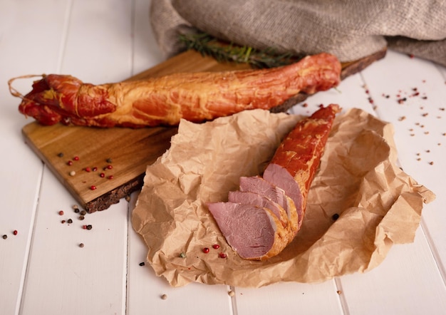 Geräuchertes Fleisch in Scheiben geschnitten auf einem Holztisch mit dem Zusatz von aromatischen Gewürzen