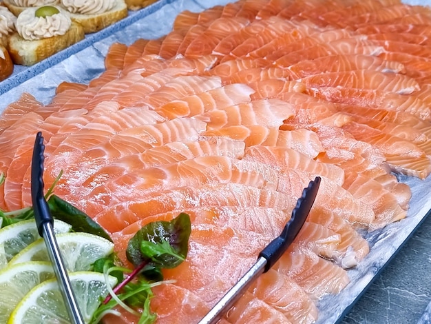 Geräuchertes Lachsfilet auf dem TischbuffetViele Stücke frischer Lachsfische werden im Open-Air-Restaurant am Strand serviert