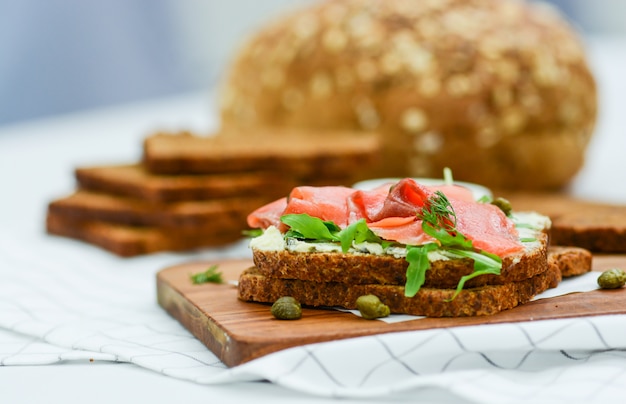 Geräuchertes Lachssandwich mit Käse, Pistazien und Salatblättern, Schwarzbrot