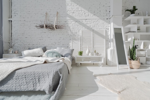 Geräumige, stilvolle, moderne, trendige Loft-Wohnung in weißen und grauen Farben voller Sonnenlicht. Mauer, Regale, Palettenbett