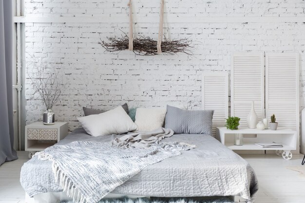 Geräumige, stilvolle, moderne, trendige Loft-Wohnung in weißen und grauen Farben voller Sonnenlicht. Mauer, Regale, Palettenbett