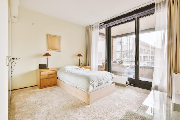 Geräumiges schlafzimmer mit teppichboden im weißen design mit zugang zum balkon eines modernen hauses