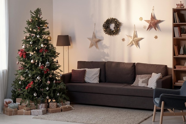 Geräumiges Wohnzimmer mit Couch, Lampe, Sessel und Weihnachtsbaum, dekoriert mit Spielzeug und Girlanden