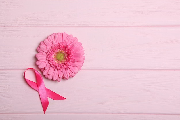 Foto gérbera de fita rosa e estetoscópio em uma vista superior de fundo colorido